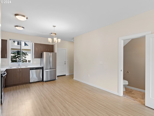 kitchen with light wood-type flooring, dark brown cabinetry, stainless steel appliances, sink, and pendant lighting