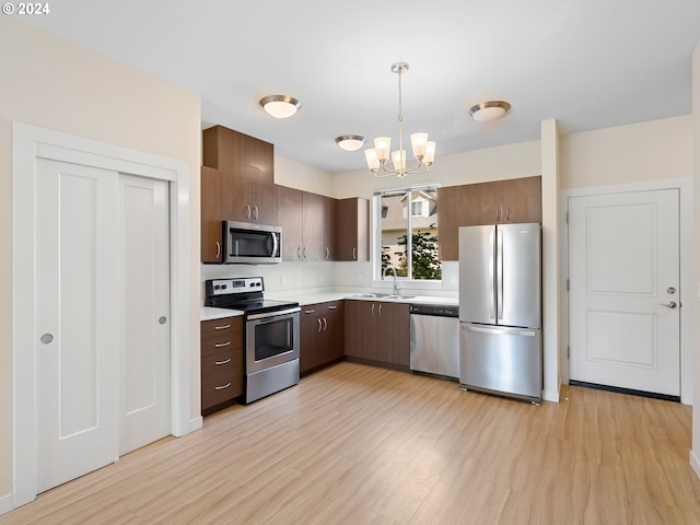 kitchen featuring sink, decorative light fixtures, light hardwood / wood-style flooring, appliances with stainless steel finishes, and a notable chandelier