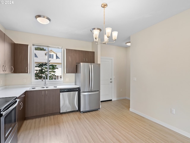 kitchen featuring light wood-type flooring, stainless steel appliances, sink, decorative light fixtures, and an inviting chandelier