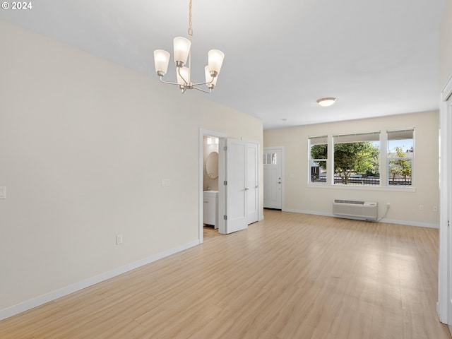 unfurnished living room featuring a wall mounted AC, light hardwood / wood-style flooring, and an inviting chandelier