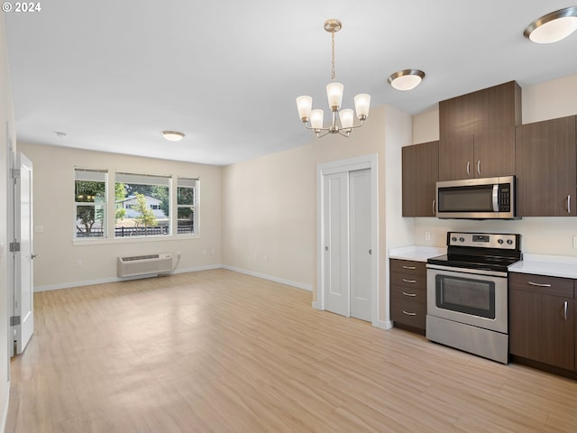 kitchen with an AC wall unit, light hardwood / wood-style floors, hanging light fixtures, and appliances with stainless steel finishes