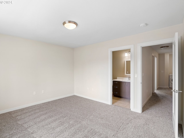 empty room with washer / dryer and light colored carpet