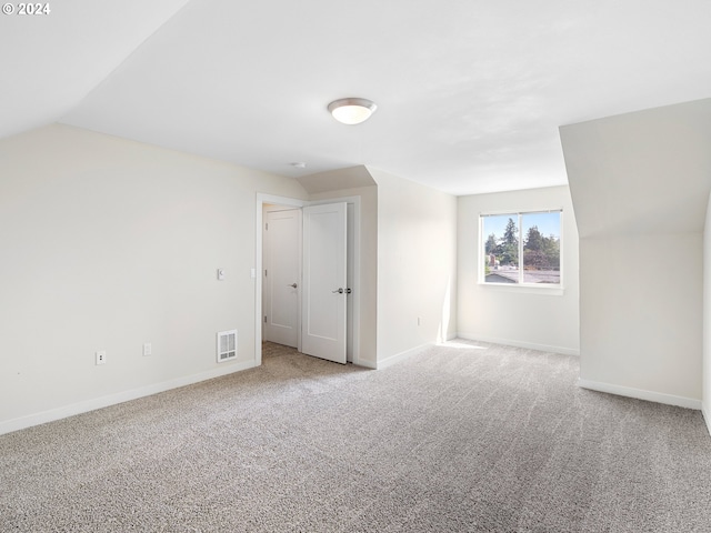 unfurnished room featuring light colored carpet and vaulted ceiling