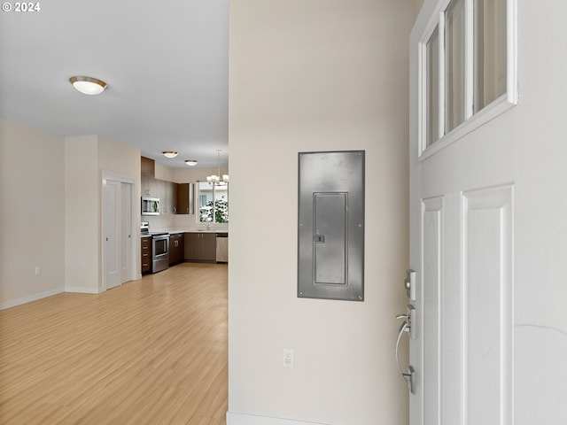 foyer with electric panel, light hardwood / wood-style flooring, and an inviting chandelier