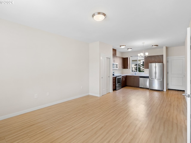 kitchen featuring sink, appliances with stainless steel finishes, decorative light fixtures, light hardwood / wood-style floors, and dark brown cabinetry