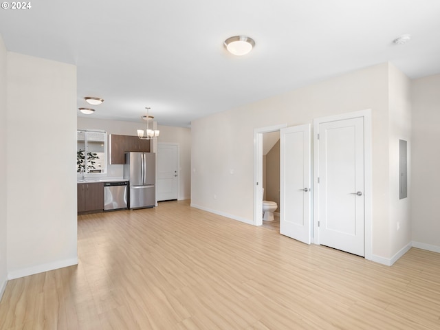 unfurnished living room with electric panel, light hardwood / wood-style flooring, and a notable chandelier