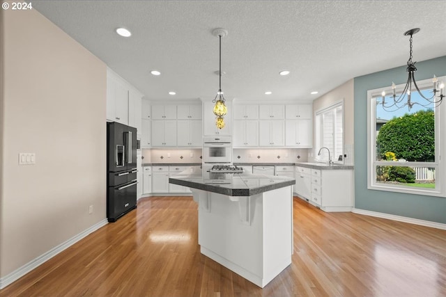 kitchen with decorative backsplash, sink, white cabinetry, and light hardwood / wood-style flooring