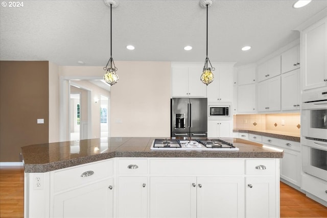 kitchen featuring light hardwood / wood-style floors, white double oven, stainless steel gas cooktop, a kitchen breakfast bar, and white cabinets