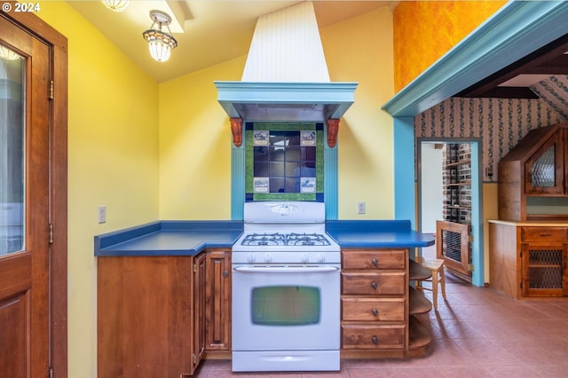 kitchen with vaulted ceiling, white gas stove, and light tile patterned flooring