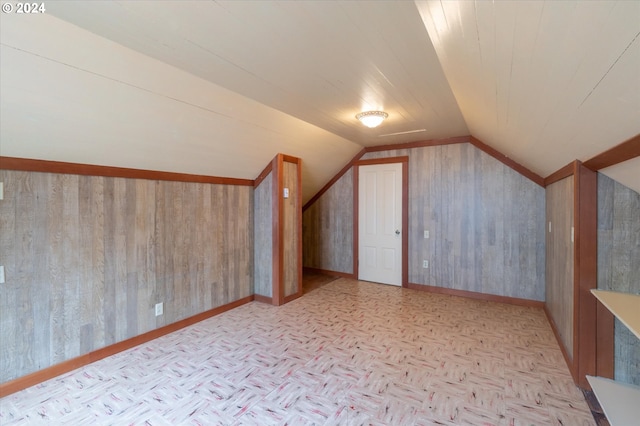 additional living space featuring light parquet floors, lofted ceiling, and wood walls