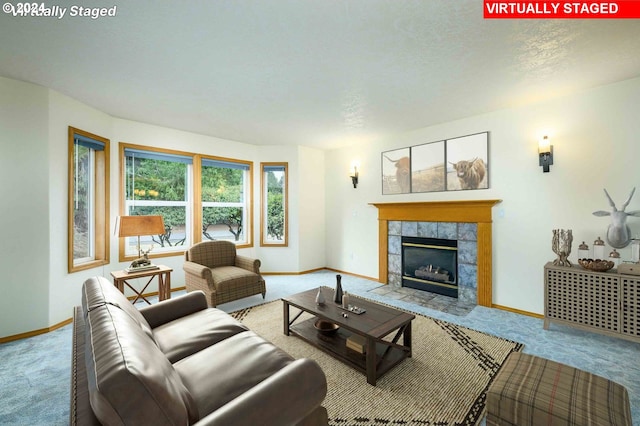 living room featuring baseboards, a tiled fireplace, and light colored carpet