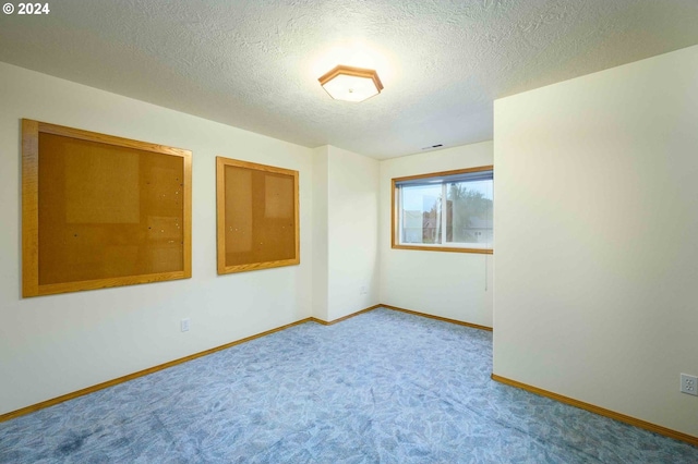 carpeted empty room with a textured ceiling and baseboards