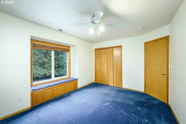 unfurnished bedroom featuring ceiling fan, dark colored carpet, and a closet