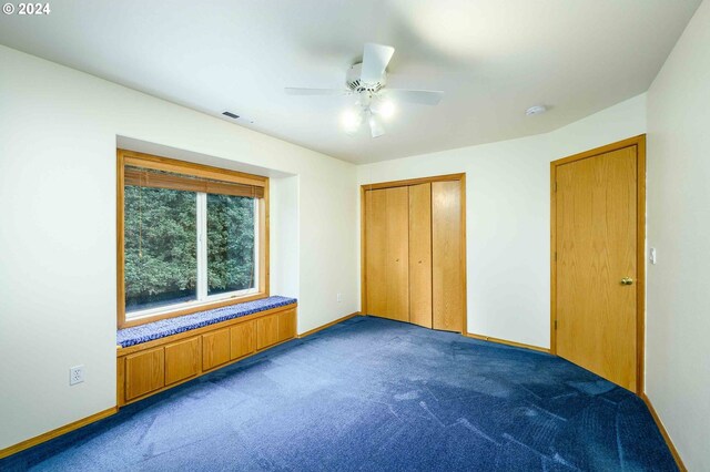 unfurnished bedroom with ceiling fan, visible vents, baseboards, a closet, and dark carpet