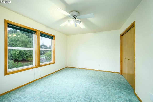 spare room with a ceiling fan, light colored carpet, and baseboards