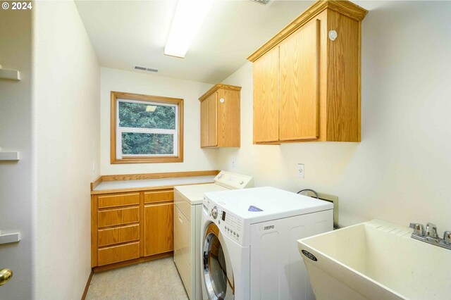 clothes washing area with washer and dryer, cabinets, and sink