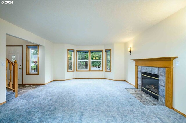 unfurnished living room featuring light colored carpet and a tile fireplace