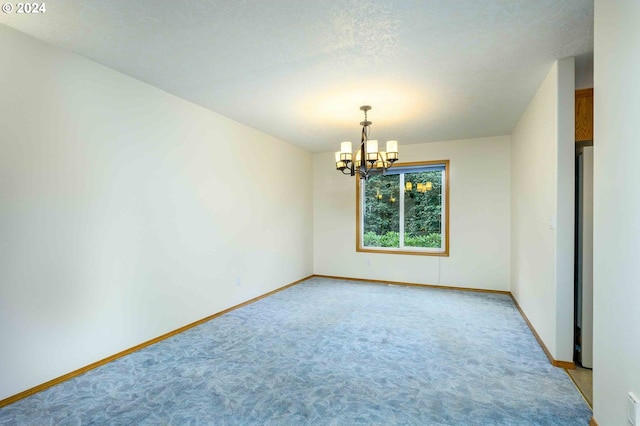 carpeted empty room with a textured ceiling and an inviting chandelier