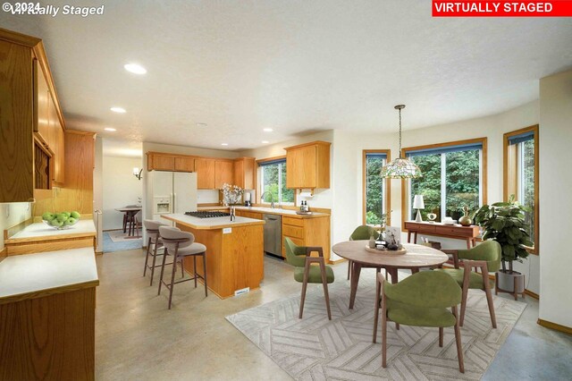 kitchen with appliances with stainless steel finishes, a breakfast bar area, a center island, and pendant lighting