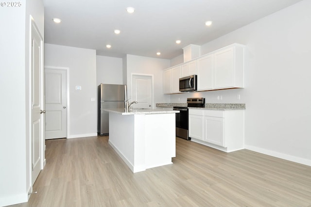 964 NE 14th St, Battle Ground, WA 98604 - kitchen featuring appliances with stainless steel finishes, light wood-style floors, a center island with sink, baseboards, and white cabinets