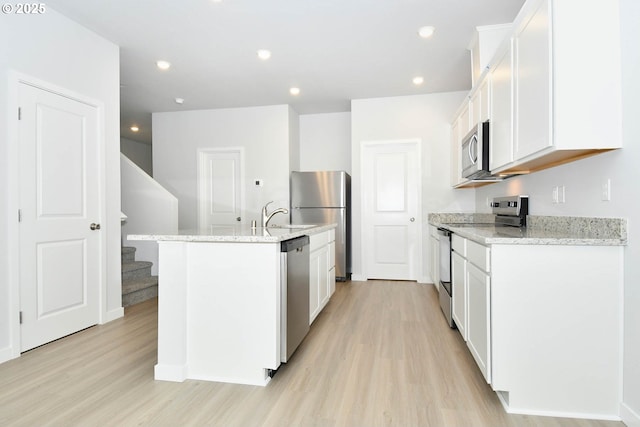 kitchen featuring light wood-type flooring, white cabinets, and stainless steel appliances