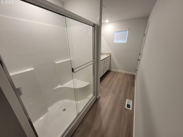 bathroom featuring baseboards, visible vents, wood finished floors, an enclosed shower, and vanity