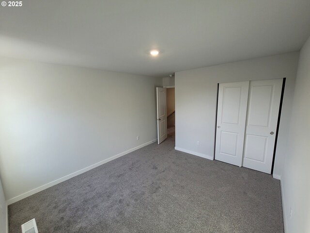 unfurnished bedroom featuring carpet floors, a closet, visible vents, and baseboards