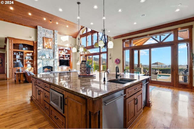 2945 SW Homesteader Rd, West Linn, OR 97068 - kitchen with stainless steel appliances, a sink, a spacious island, a stone fireplace, and light wood-style flooring