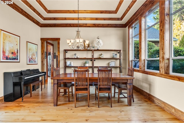 dining space featuring ornamental molding, light hardwood / wood-style floors, a notable chandelier, and a tray ceiling