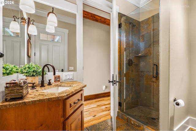 bathroom featuring vanity, hardwood / wood-style floors, a shower with door, and ornamental molding