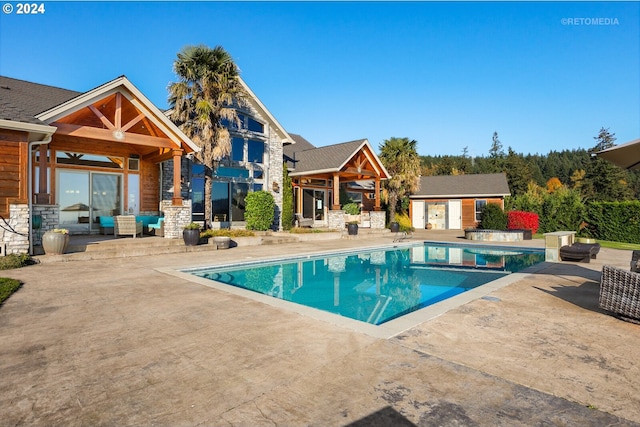 view of swimming pool featuring an outbuilding, a jacuzzi, and a patio area