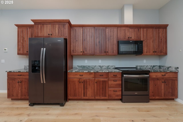 kitchen with light wood-type flooring, brown cabinetry, stainless steel appliances, and dark stone countertops