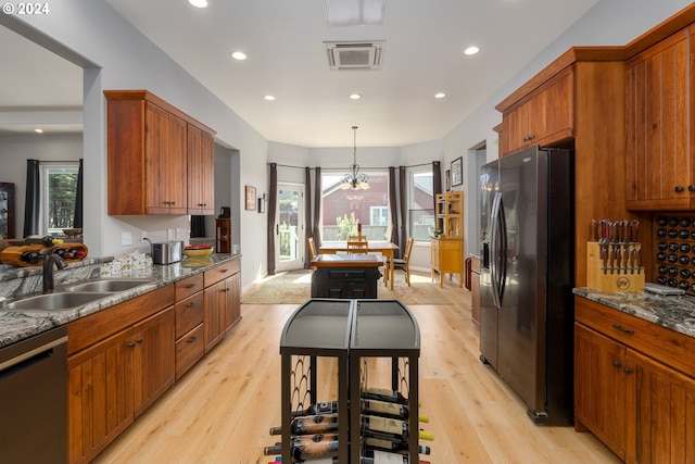 kitchen featuring light hardwood / wood-style floors, stainless steel appliances, stone counters, and sink