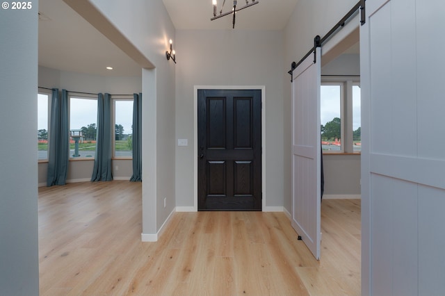 entrance foyer featuring a healthy amount of sunlight, light wood-style flooring, baseboards, and a barn door