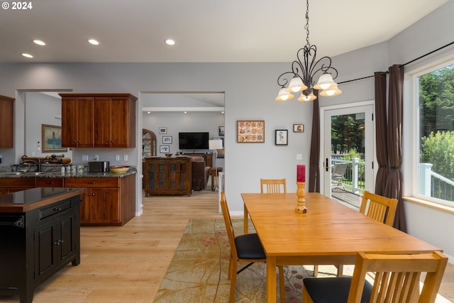 dining space with light wood-type flooring, sink, and a notable chandelier