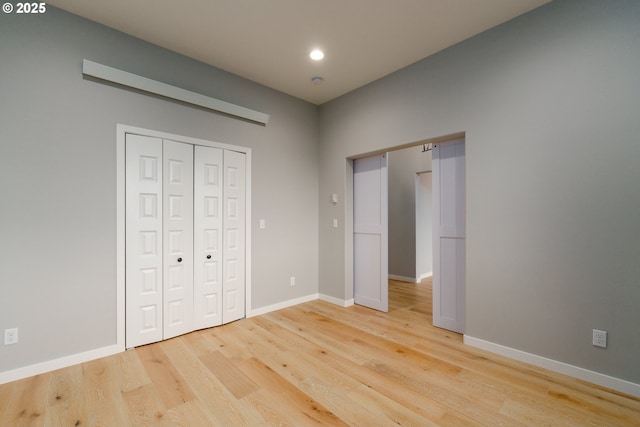 unfurnished bedroom with a closet, recessed lighting, light wood-style flooring, and baseboards