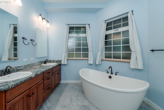 bathroom featuring a freestanding tub, a sink, baseboards, and double vanity