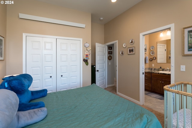 bedroom with connected bathroom, sink, light carpet, and a closet