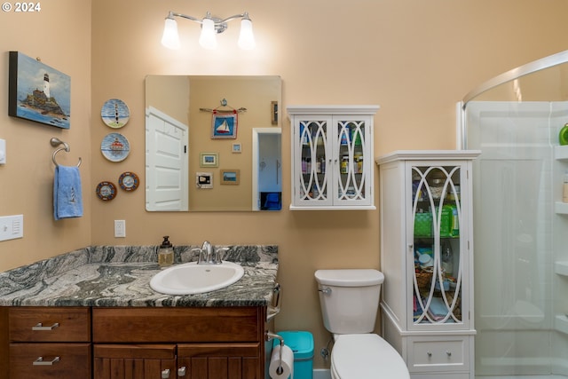 bathroom featuring vanity, toilet, and a shower with door