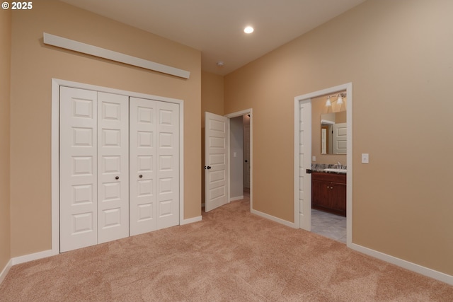 unfurnished bedroom with recessed lighting, a closet, ensuite bathroom, light carpet, and baseboards