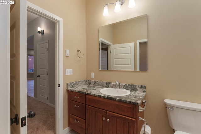 bathroom featuring baseboards, vanity, and toilet