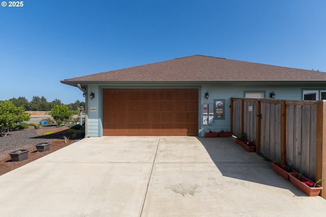 exterior space with a garage, roof with shingles, fence, and driveway