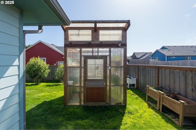 exterior space featuring a yard, an exterior structure, a fenced backyard, a garden, and an outdoor structure