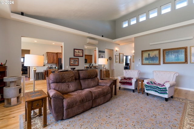 living room with light hardwood / wood-style flooring, a wall mounted air conditioner, and high vaulted ceiling