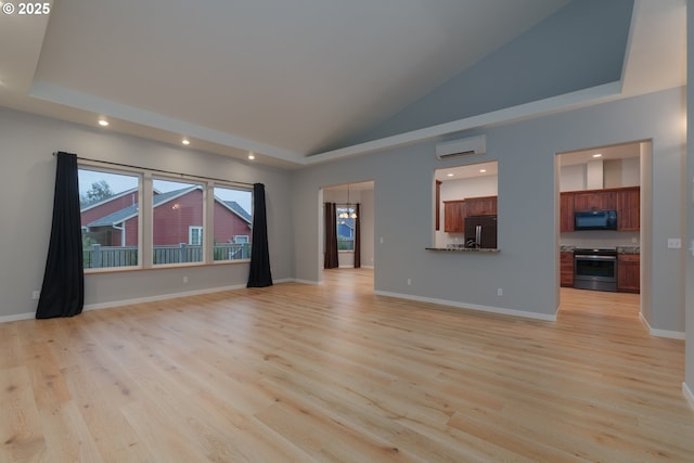 unfurnished living room with an AC wall unit, light wood finished floors, high vaulted ceiling, and baseboards