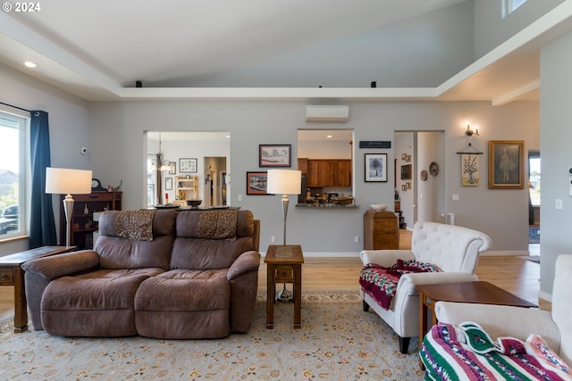 living room with vaulted ceiling, an inviting chandelier, light hardwood / wood-style floors, and a wall mounted AC