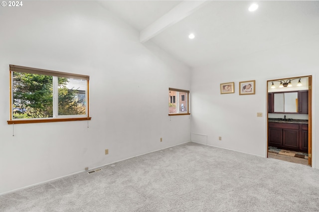 carpeted empty room featuring beamed ceiling and high vaulted ceiling