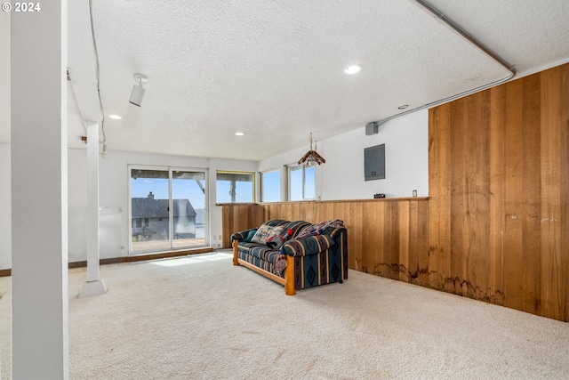 living room with a textured ceiling, carpet flooring, and wooden walls