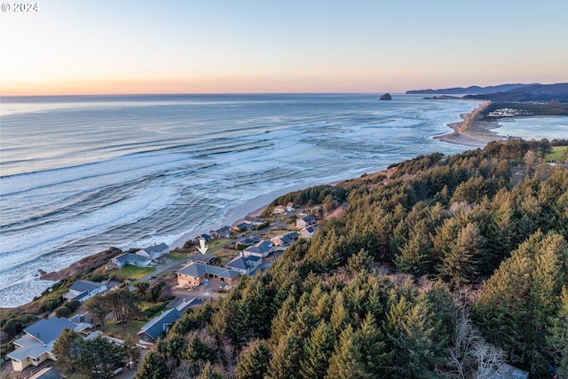 aerial view at dusk with a view of the beach and a water view