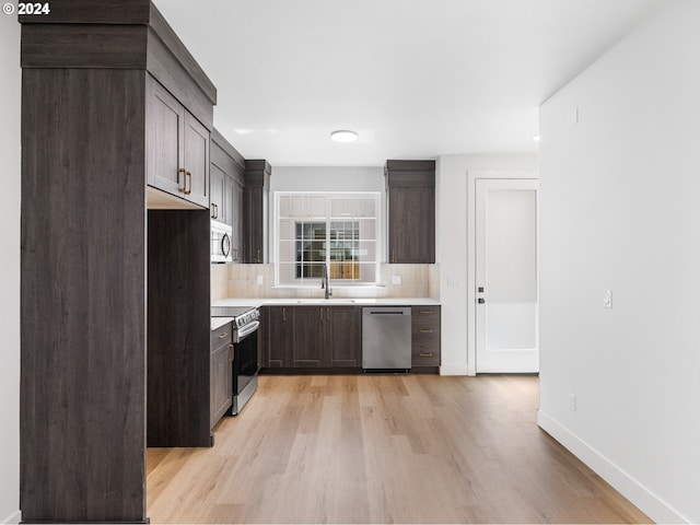 kitchen with appliances with stainless steel finishes, light hardwood / wood-style flooring, dark brown cabinets, and decorative backsplash